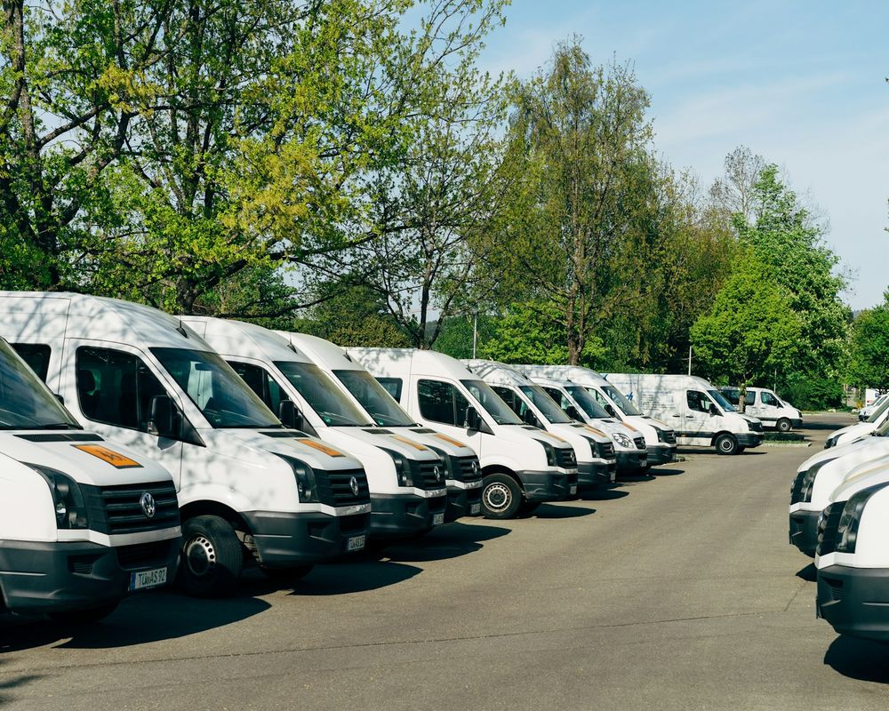 Flota białych busów gotowych do wyjazdu na trasy do Niemiec